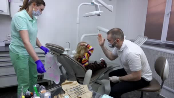 Little cute girl is giving a high five to her dentist — Stock video