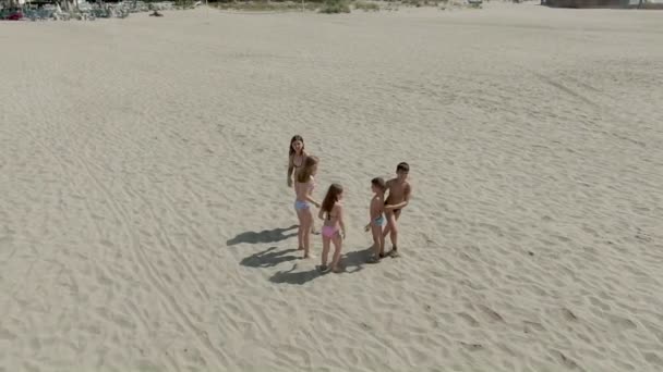 Five children in swimsuits running on the sand beach — Stock video
