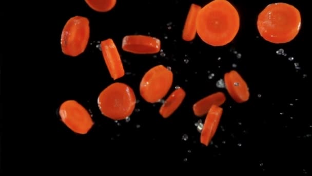 Fresh slices of organic carrots flying with splashes of water — Stok video