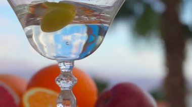 Yeşil bir zeytin, Martini ile bardağa düşüyor.