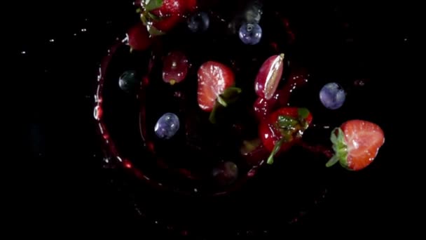 Различные ягоды летят вверх с брызгами сока на черном фоне — стоковое видео