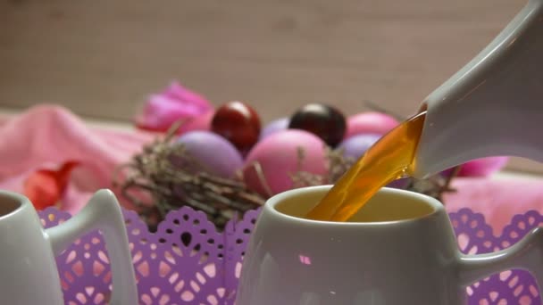 Té vertido en la taza en el fondo de los huevos de Pascua de color rosa — Vídeo de stock