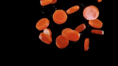 Fresh choped organic carrots flying up on a black background