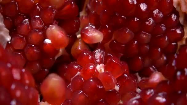 Close up of juicy ripe red pomegranate seeds fall on a cut fruit — Stockvideo