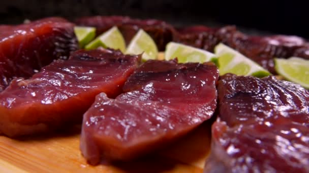 Pedaços de atum levemente salgado e limão estão deitados em uma tábua de corte — Vídeo de Stock