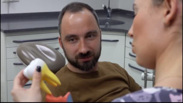 Dentista está mostrando um modelo de dente para o paciente — Vídeo de Stock
