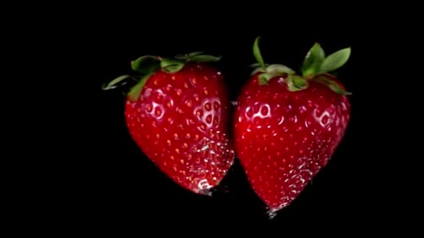 Two large juicy strawberries are flying towards each other — Stock Video