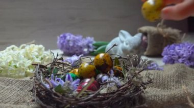 Çocuk eli yuvaya küçük renkli bir Paskalya yumurtası koyar.