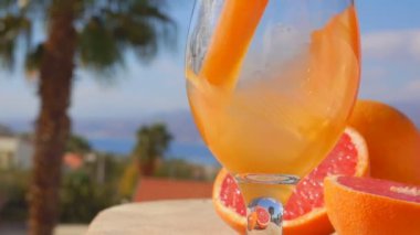Close up of a grapefruit juice poured into a glass on the background of the sea