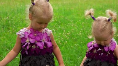 Two little sisterss in a purple fantasy dresses are looking at the camera