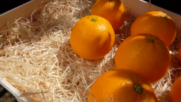 Mano pone una deliciosa naranja jugosa en una caja de madera — Vídeos de Stock