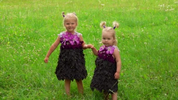 Duas irmãzinhas em um vestido de fantasia roxo feito de folhas e flores — Vídeo de Stock