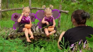 Kadın fotoğrafçı kelebek kanatları takan kızların fotoğraflarını çekiyor.