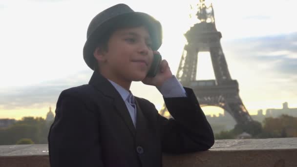 Chlapec mluví po telefonu na pozadí Eiffelovy věže — Stock video