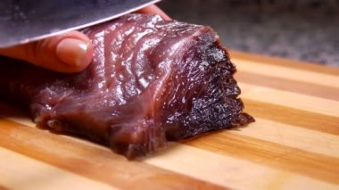 Close up of knife slowly cutting tuna filet into slices on a board