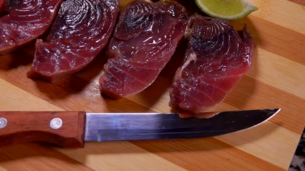 Panorama from the knife to the lightly salted tuna and lime lying on a board — Stockvideo