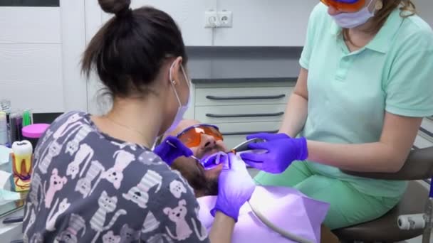 Стоматолог робить професійну чистку зубів за допомогою медсестри — стокове відео
