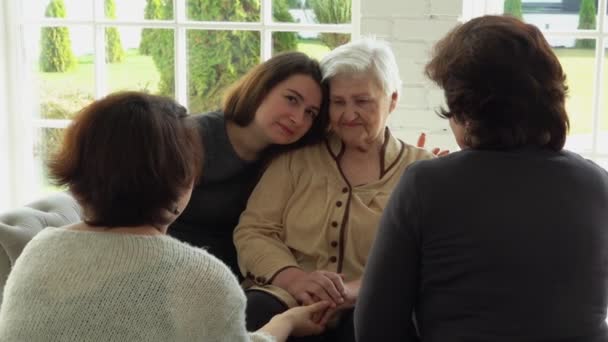 Anciana mujer de pelo blanco está sentada con su hija y nietas — Vídeo de stock