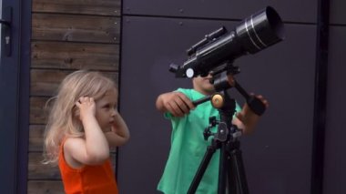 Küçük bir kız ve tatlı bir oğlan teleskopla gökyüzünü keşfediyorlar.