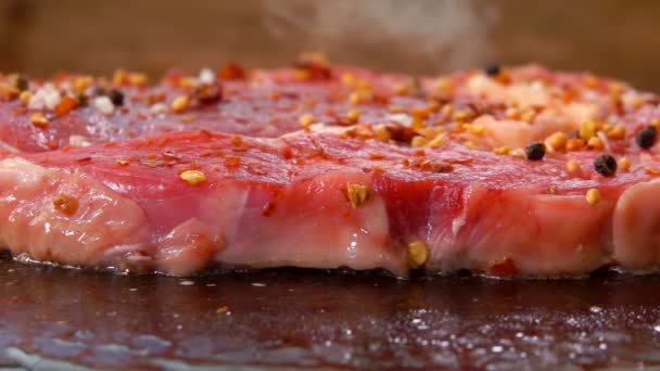 Супер крупный план сырого сочного говяжьего стейка с перцем и пряностями — стоковое видео
