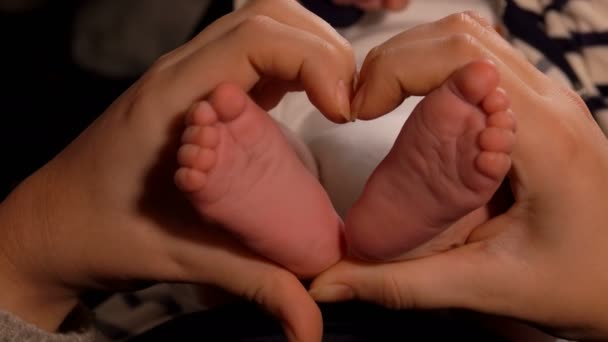 Las manos femeninas están haciendo un gesto de corazón con pequeños pies adorables en un centro — Vídeo de stock