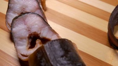 Bambu bir tahtanın üzerinde duran füme yılan balığı dilimlerinin üst görüntüsü 