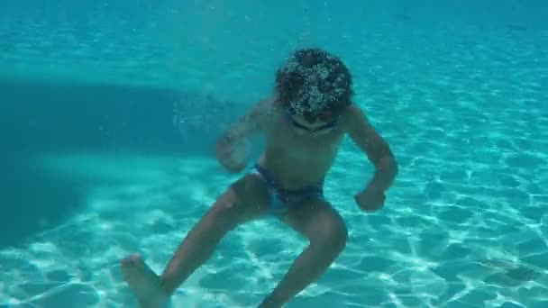 Petit garçon plonge sous l'eau dans la piscine et agite ses mains — Video