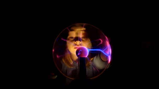 Mooi meisje beweegt haar vingers op het oppervlak van de plasma tesla bal — Stockvideo