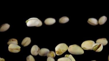 Taze yeşil şam fıstıkları siyah arka planda uçuşuyor.