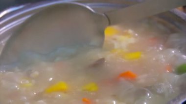 Bir kaşık haşlanmış mantar çorbasını sebzelerle karıştırıyor.