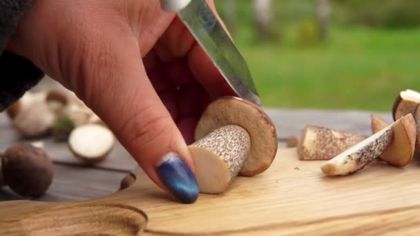 Close-up van een vrouwelijke handen die een vers geplukte paddenstoel snijden op een houten plank — Stockvideo