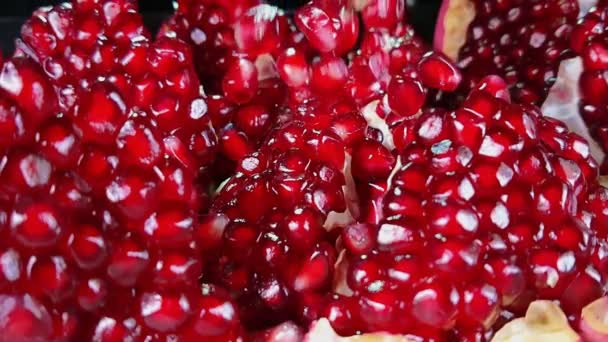 Saftiga röda kärnor av moget granatäpple som faller på den brutna frukten — Stockvideo