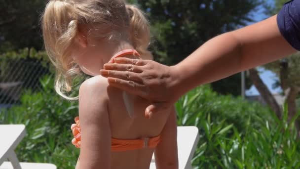 Χέρι αλείφει τον ήλιο προστατευτική κρέμα στο μικρό κορίτσι πίσω και τους ώμους — Αρχείο Βίντεο