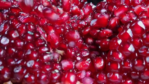 Närbild av saftiga röda kärnor av moget granatäpple som faller på den brutna frukten — Stockvideo