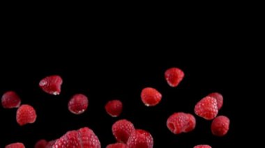 Ahududular yukarı uçuyor ve yavaş çekimde siyah arka plana düşüyorlar.