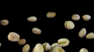 Taze yeşil şam fıstıkları siyah bir arka planda zıplar.