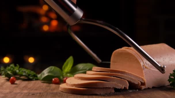 Nóż smyczkowy wycina foie gras na desce na tle kominka — Wideo stockowe