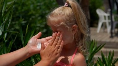 Sarışın kızın yüzüne güneş koruyucu krem sür. 