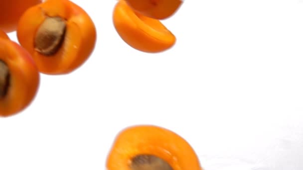 Zralé šťavnaté meruňky půlky létají diagonálně na bílém pozadí — Stock video