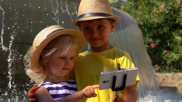Malý chlapec a dívka v slaměných čepicích dělají selfie na smartphonu
