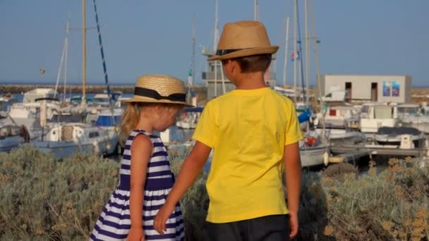 Chlapec a rozkošné v kloboucích se dívají na nábřeží přístavu jachty — Stock video