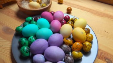 Masadaki gri tabakta çok renkli Paskalya tavuğu ve bıldırcın yumurtası.