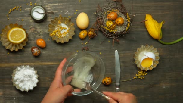 Bovenaanzicht op de handen kloppen ei wit in een glazen kom om koninklijke glazuur te maken — Stockvideo