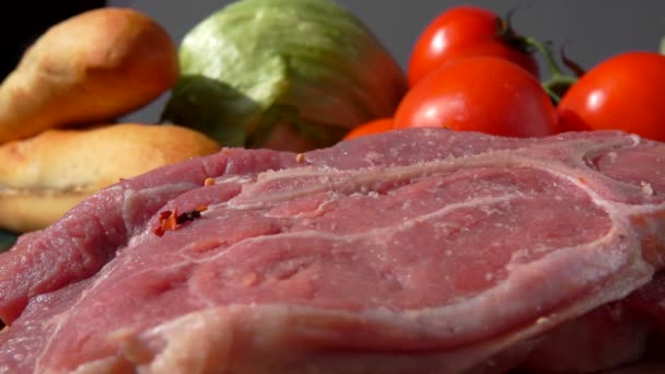 Mistura de especiarias está caindo em um bife de porco no fundo de legumes — Vídeo de Stock