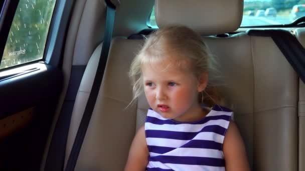 Schöne blonde Mädchen mit Hüten reitet im Auto auf dem Rücksitz — Stockvideo