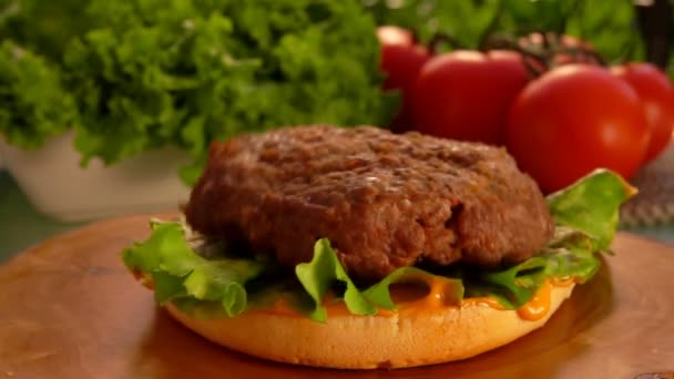 Deliciosa chuleta de carne de res está cayendo sobre el pan de hamburguesa con ensalada verde — Vídeos de Stock