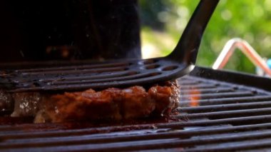 Hamburger için pirzola ızgaraya spatula ile bastırılır ve alev alır.