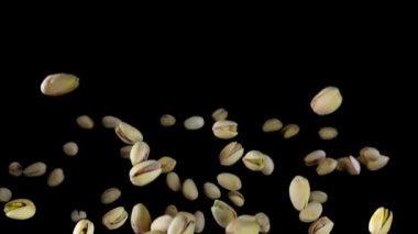 Yeşil fıstıklar siyah arka planda zıplarlar.