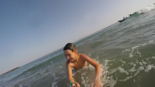 Sonriente niño está corriendo y nadando a través del agua del mar — Vídeos de Stock