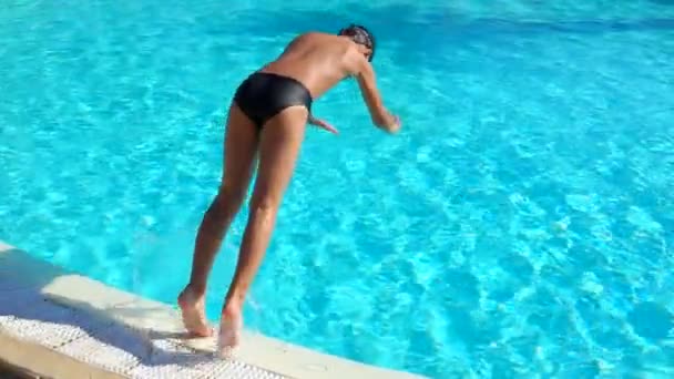 Мальчик в плавательных очках прыгает с сальто в бассейн — стоковое видео